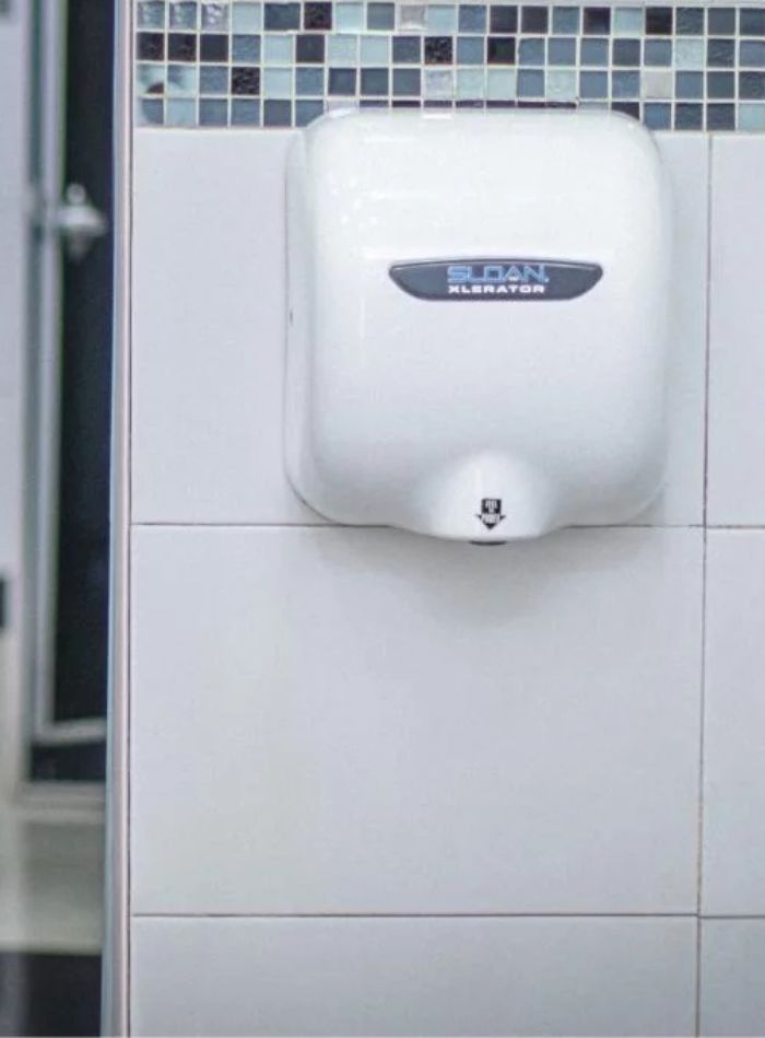 Sloan Xlerator high-speed automatic hand dryer installed over decorative mosaic tiles, designed for efficient and sustainable hand drying.