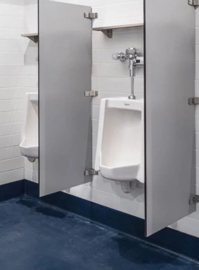 White urinals with gray dividers and Sloan automatic flushometers, combining functionality and privacy in restroom design.