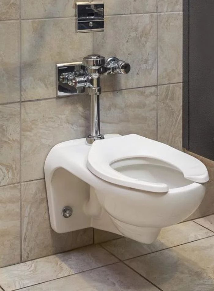 Wall-mounted toilet with chrome Sloan flushometer, offering a modern and efficient design ideal for high-traffic spaces.