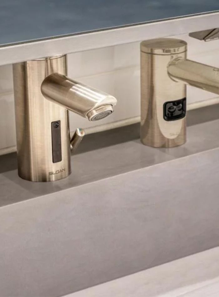 Close-up of Sloan automatic faucets with a satin finish, integrating advanced technology for efficient water use.