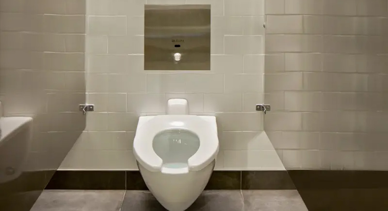 wall-mounted toilet with a concealed Sloan flushometer, designed for efficiency, hygiene, and modern aesthetics. The stainless-steel flush panel highlights durability and vandal resistance, ideal for high-traffic spaces like the Chicago Post Office, where functionality, sustainability, and contemporary design converge.