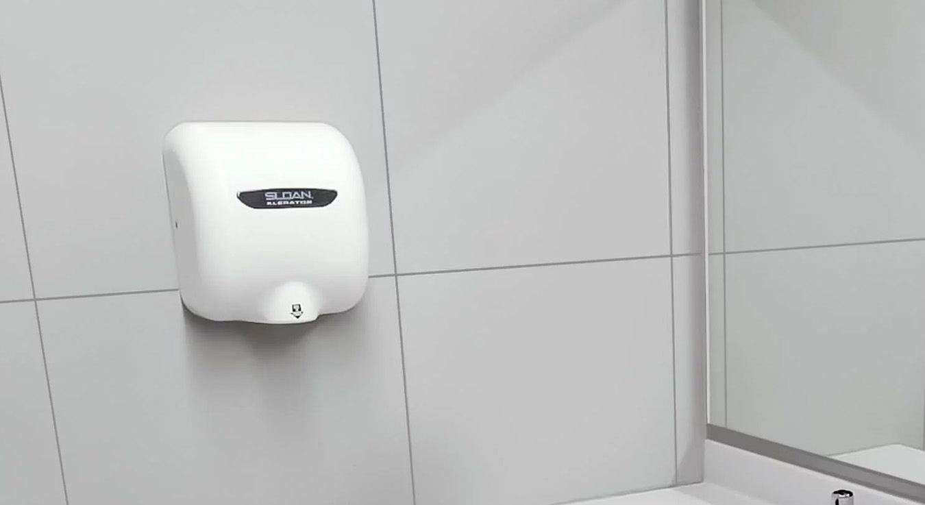 a modern restroom featuring double sinks with Sloan manual faucets and wall-mounted automatic hand dryers.