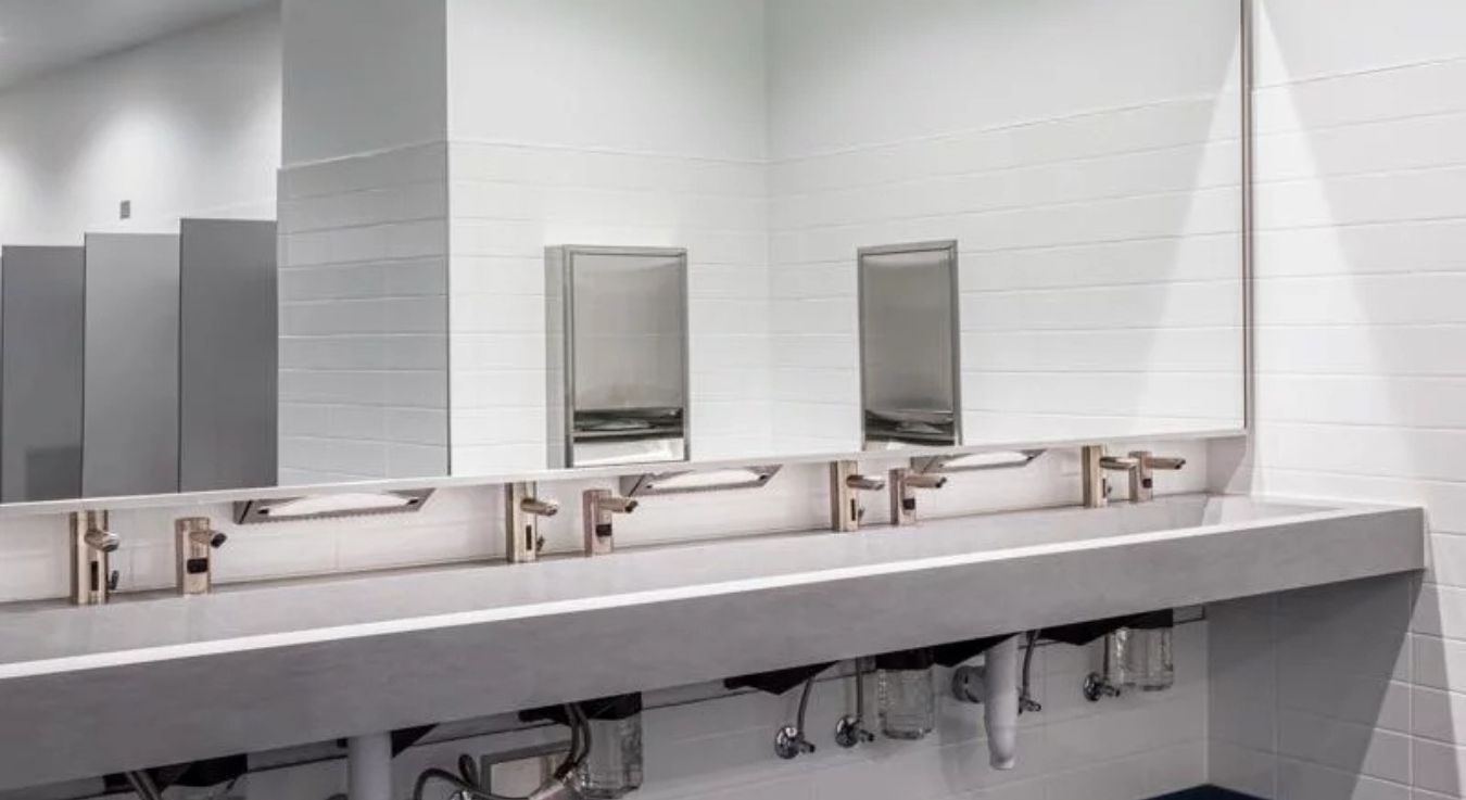 Spacious sinks with gray finishes and Sloan touch-free faucets, designed to provide a hygienic, hands-free experience in a high-traffic environment.
