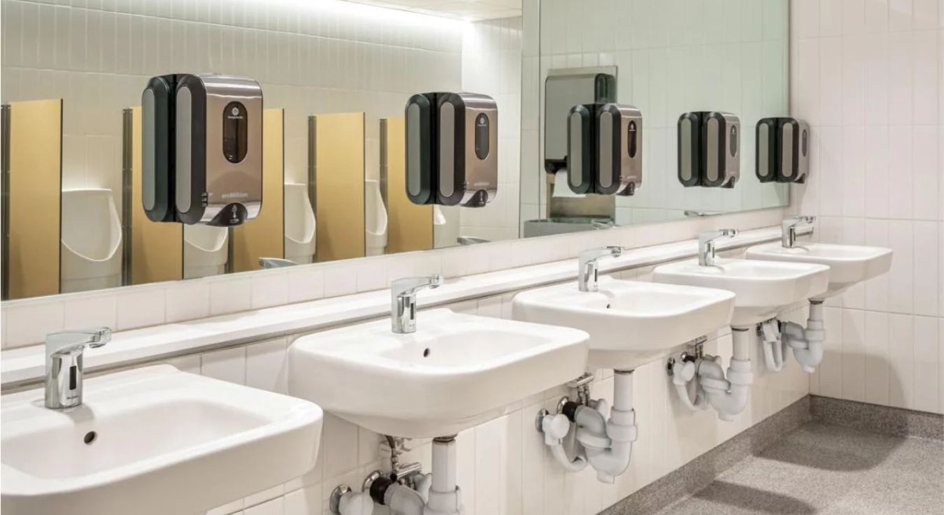 Modern sinks with touch-free automatic faucets and stainless steel soap dispensers, designed to promote hygiene and water efficiency.