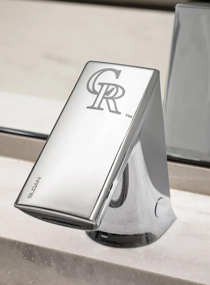 Sloan automatic faucet with a chrome finish and the Colorado Rockies (CR) logo engraved on top, highlighting the branding of Coors Field. The faucet’s sleek, angular design merges functionality with elegance, providing a hygienic, touch-free experience suitable for high-traffic sports facilities.