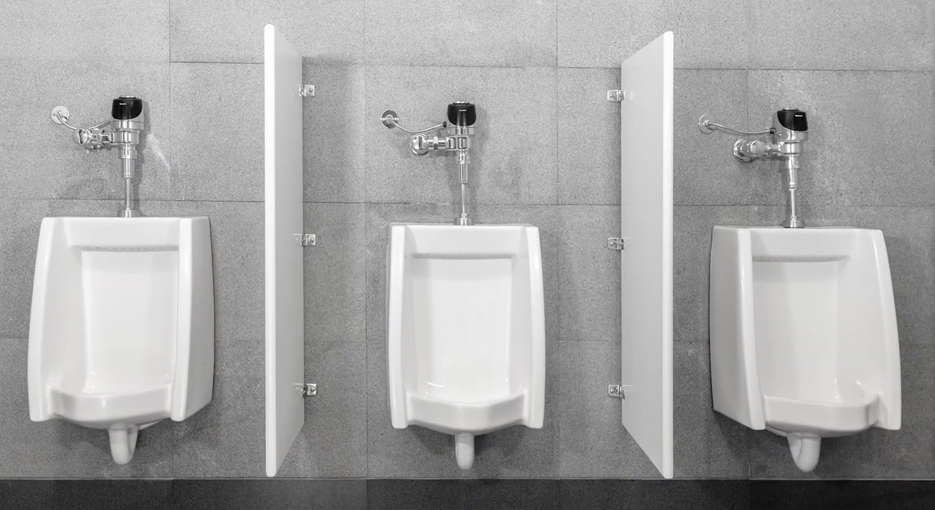 three white urinals with automatic sensor flush valves and side partitions against gray tiled walls. The clean and orderly design conveys modernity and hygiene, typical of well-equipped public restrooms.