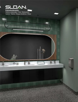 elegant contemporary restroom featuring Sloan automatic faucets. The design combines green tones with wood and black details, while a large oval mirror adds a sense of spaciousness. Warm lighting and polished finishes convey modernity and sophistication.