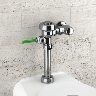 Sloan manual flushometer in polished chrome finish with green handle, installed above a toilet against a light beige stone wall.