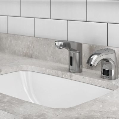 Modern sink with Sloan automatic soap dispenser and faucet in chrome finish on a light stone countertop.