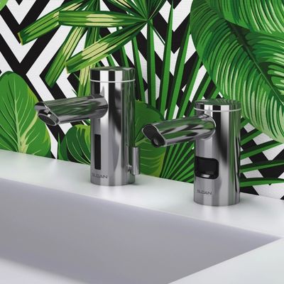 Sloan automatic faucet and soap dispenser in chrome finish, installed on a white sink with a tropical leaf and black-and-white patterned background.