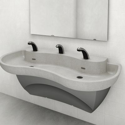 Lavabo con forma ondulada y tres grifos automáticos Sloan, instalado frente a una pared de azulejos blancos con un espejo rectangular encima.