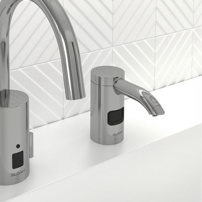 Sloan automatic faucet and soap dispenser in chrome finish, installed on a white countertop with a geometric white tile background.