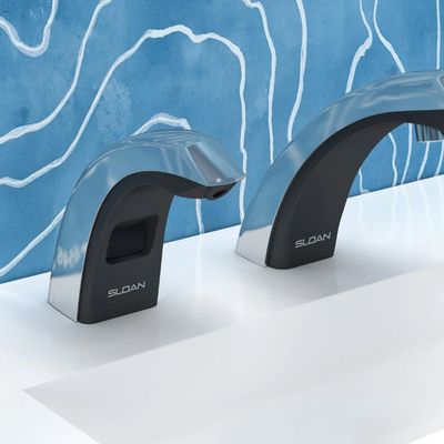 Sloan automatic faucet and soap dispenser in dual-tone black and chrome finish, installed on a white sink with a blue background featuring fluid line patterns.