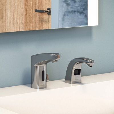 Sloan automatic faucet and soap dispenser in chrome finish, installed on a white sink with a light blue wall and wooden-framed mirror.