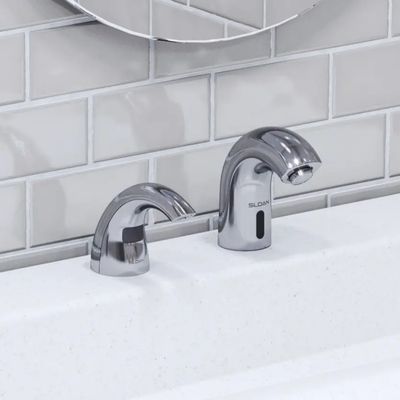 Sloan automatic faucet and soap dispenser in chrome finish, on a white sink with a gray subway tile background.
