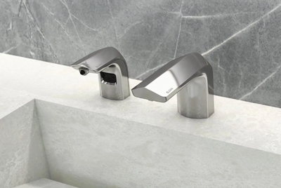 a set of Sloan® automatic dispensers featuring a modern chrome finish, installed above a light-colored solid surface sink.