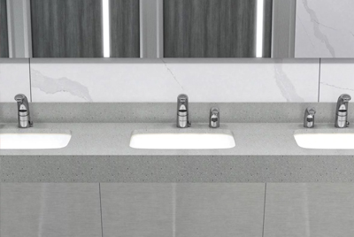 a row of sinks with Sloan® electronic faucets, set in a light-gray solid surface countertop.