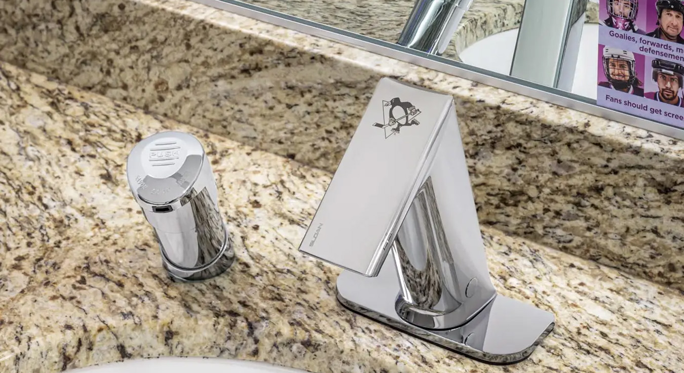 Sloan touchless faucet installed on a granite countertop, featuring the Pittsburgh Penguins logo, located at PPG Paints Arena. This model blends elegance and performance with sensor-activated technology that minimizes water waste and enhances hygiene.