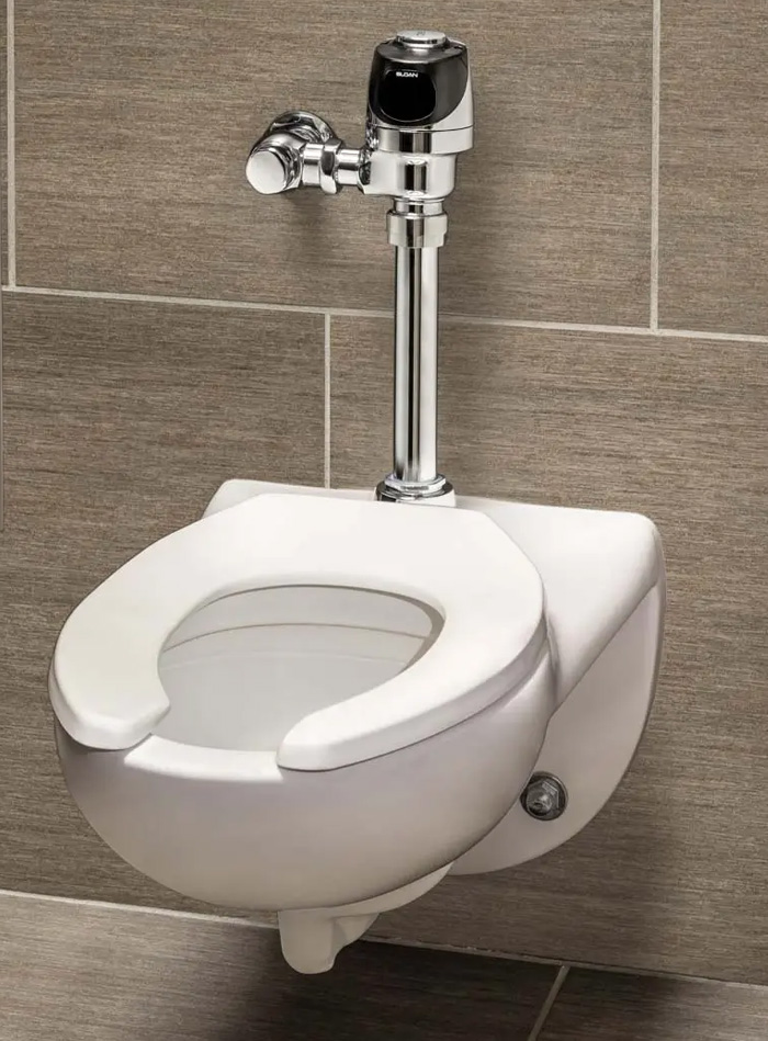 Sloan wall-mounted water closet installed at PPG Paints Arena. It features a modern design paired with a chrome automatic flush valve, perfect for high-traffic environments prioritizing touch-free efficiency and hygiene. The neutral tile background complements the clean, contemporary look of the restroom.