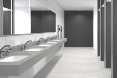 a contemporary corporate-style restroom, featuring a long integrated sink counter with Sloan® automatic chrome faucets.