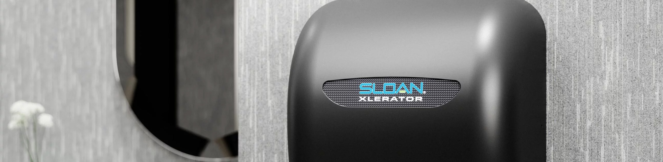 a Sloan® XLERATOR® hand dryer in a matte black finish, mounted next to a sensor-activated faucet.