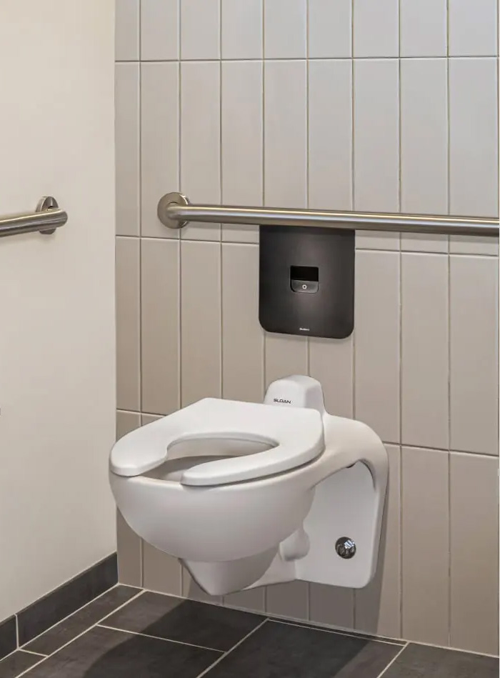 a Sloan wall-mounted toilet with a concealed automatic flush valve, installed in a modern corporate restroom at SPC Mechanical Headquarters.