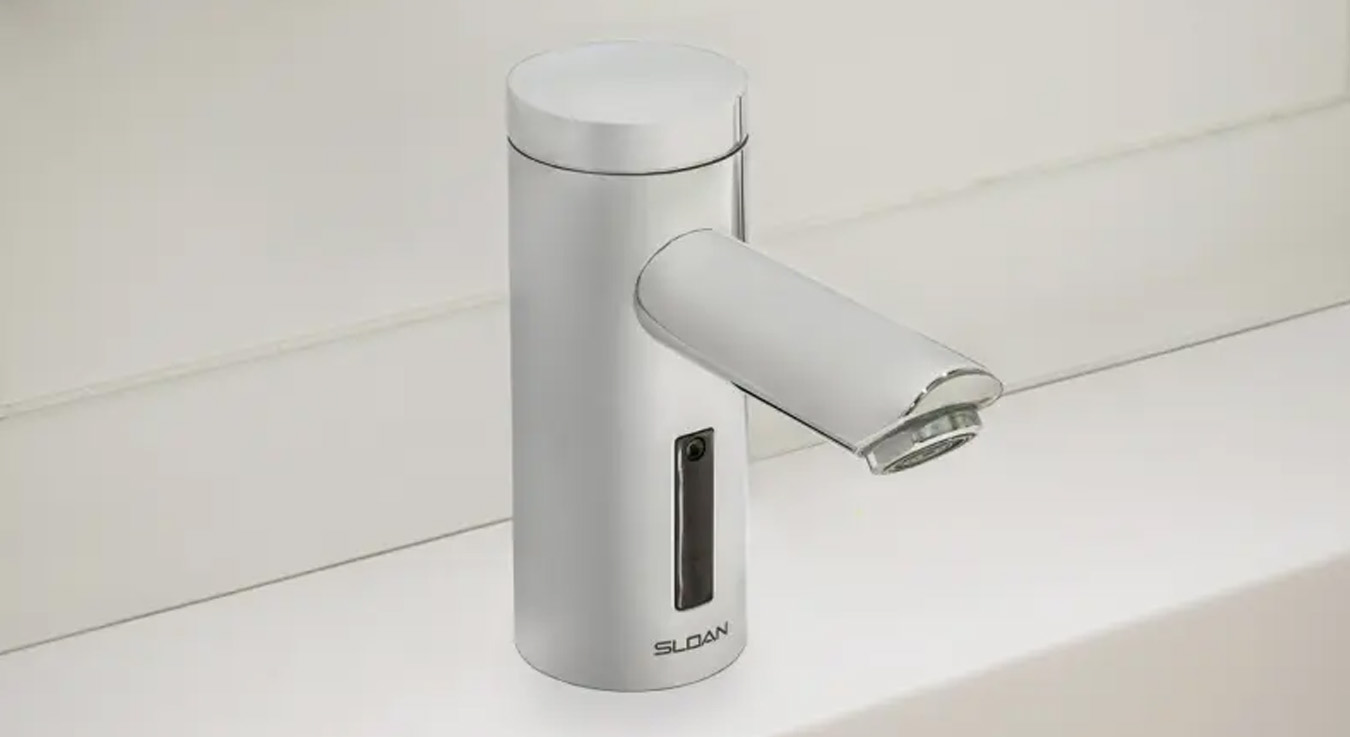 a Sloan automatic faucet featuring an integrated infrared sensor, a cylindrical design, and a durable chrome finish. Its sleek, modern aesthetic makes it ideal for institutional or educational settings, providing a touch-free, water-efficient handwashing solution.