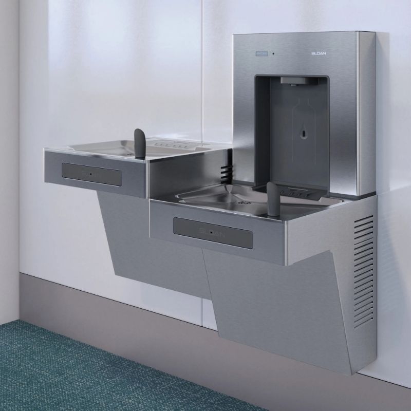 Sloan hydration station with dual stainless steel drinking fountains and a bottle filler, installed on a white wall above a carpeted floor.