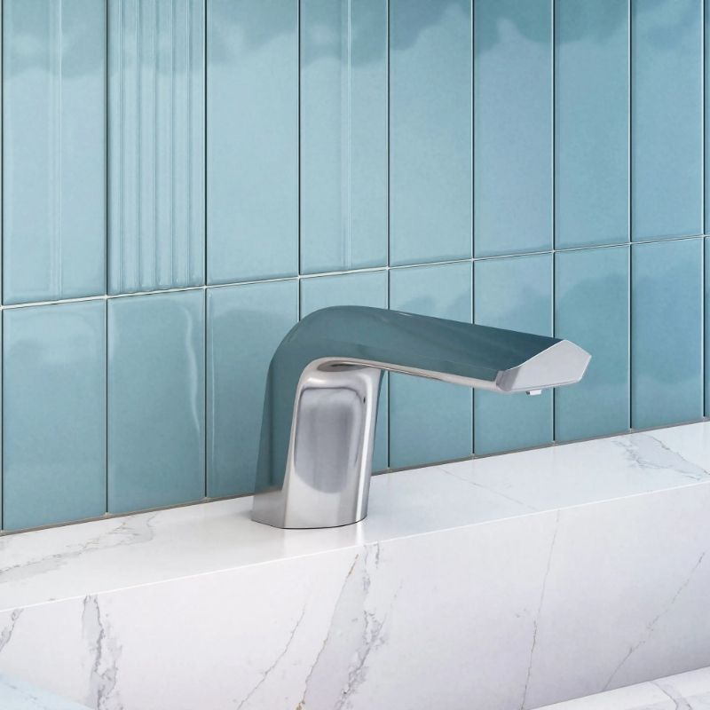 Sloan automatic chrome faucet with curved design, mounted on a white marble countertop with glossy blue tile background.