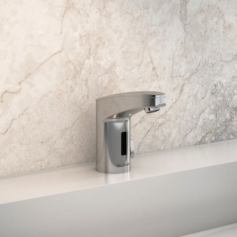 Sloan automatic chrome faucet with modern design, on a white countertop with a light beige marble backsplash.