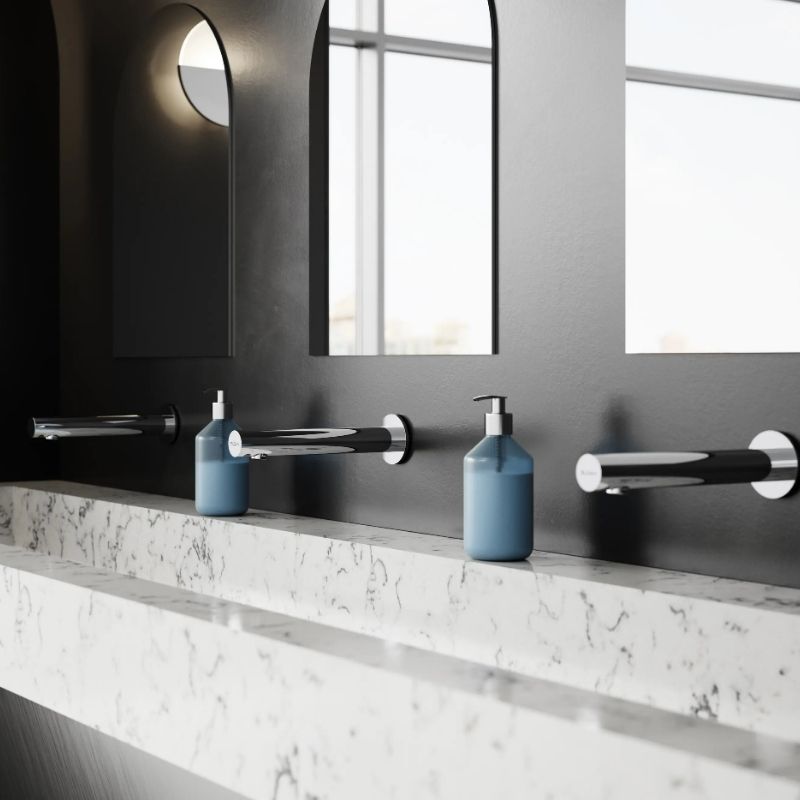 Sloan wall-mounted automatic faucets in black and chrome finish, installed above a white marble sink with arched mirrors on a dark wall.