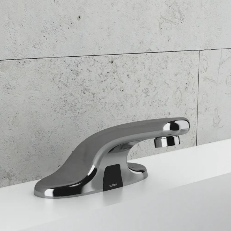 Sloan low-profile automatic chrome faucet installed on a white sink with textured gray tile background.