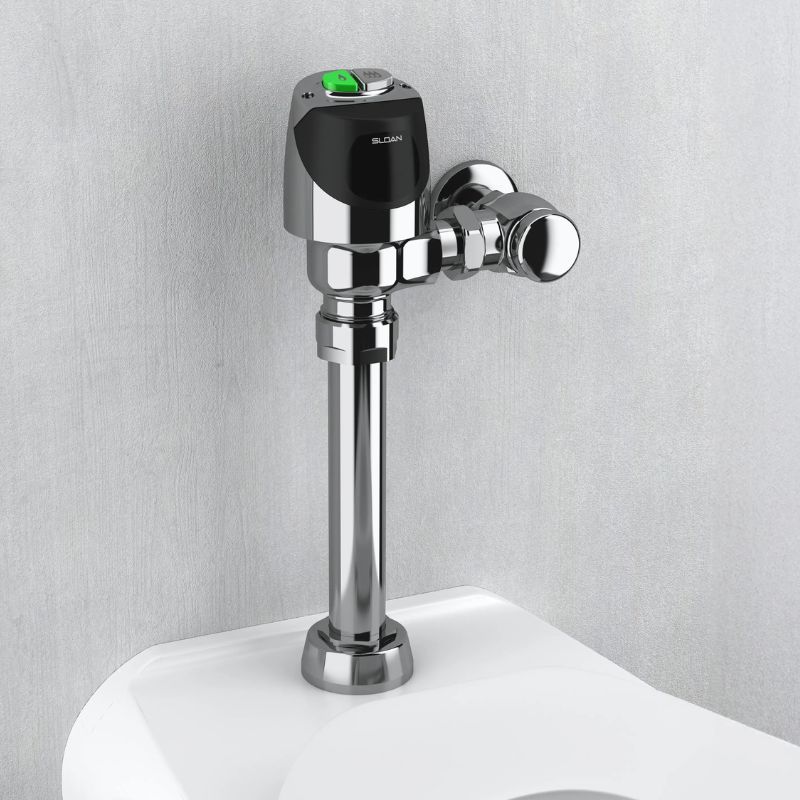 Sloan automatic flushometer with green indicator on top, installed above a toilet against a light gray wall.