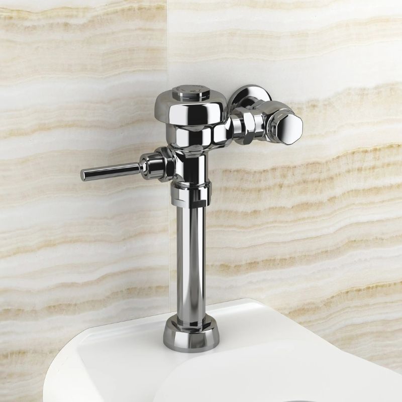 Sloan manual flushometer in polished chrome finish installed above a toilet against a beige veined marble wall.