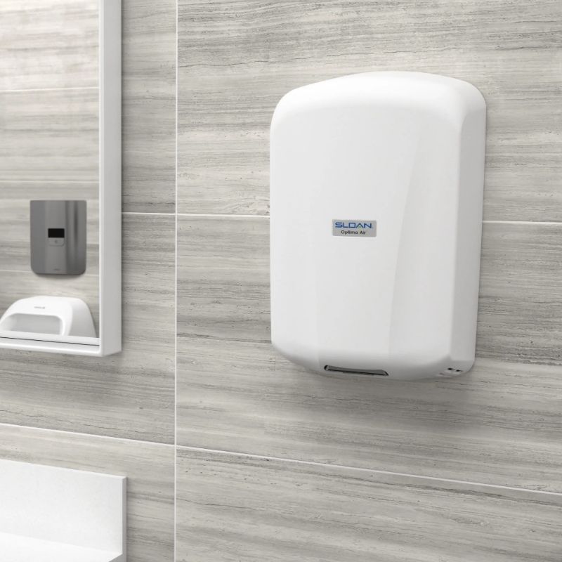 White Sloan Optima Air hand dryer mounted on a gray tiled wall in a modern restroom.
