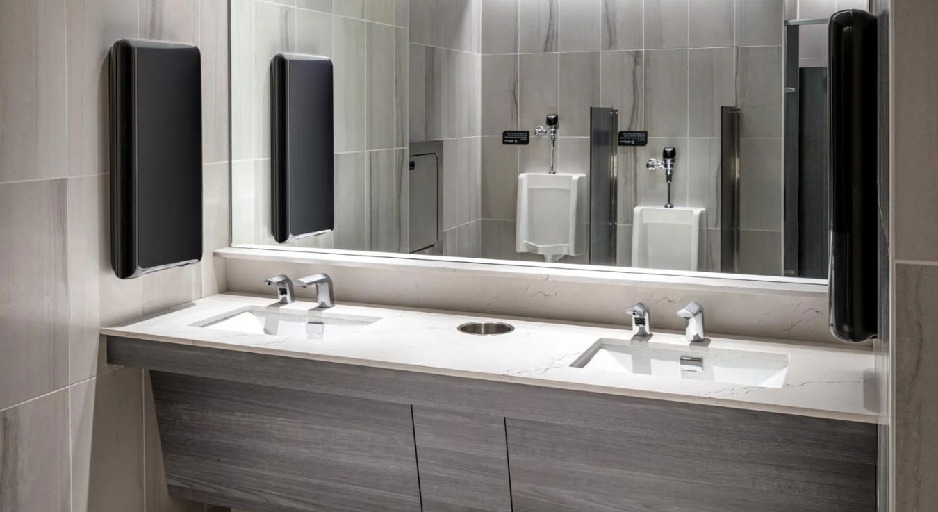 Contemporary sinks with automatic faucets and light marble finishes, complemented by built-in hand dryers in an elegant and functional setting.