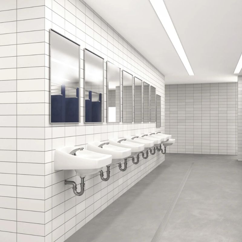 Spacious public restroom with wall-mounted sinks, automatic faucets, and mirrors aligned over white tiled walls.