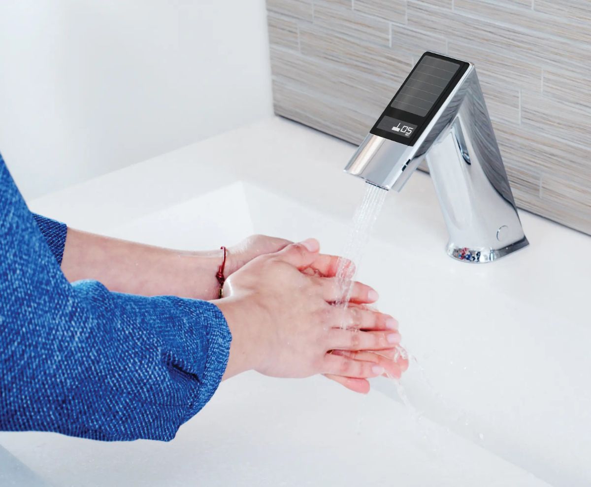 Persona lavándose las manos bajo un grifo con sensor alimentado por energía solar, diseñado para promover la higiene y la eficiencia energética.