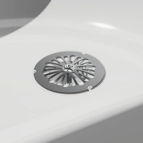 Sloan metal drain cover on a white porcelain surface, designed to optimize water flow in sinks or urinals.