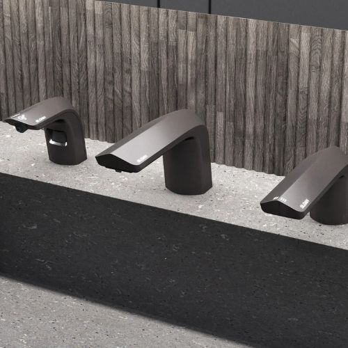 Three Sloan countertop hand dryers in a dark finish with a modern design, installed on a polished concrete surface.