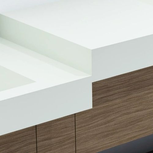 Detalle de un lavabo blanco de superficie sólida con un mueble de madera debajo, que resalta el diseño moderno y de bordes limpios.