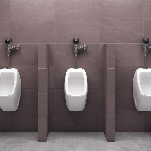 Row of Sloan urinals with automatic flush valves in a modern restroom with privacy dividers.