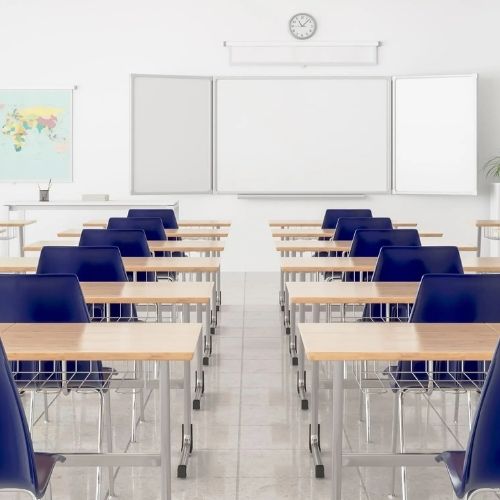 Empty modern classroom with blue chairs, wooden desks, and a clean whiteboard at the front.
