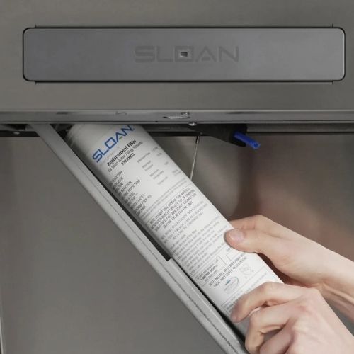 Hands replacing the water filter cartridge in a Sloan bottle filler.