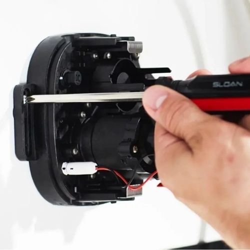Hand installing Sloan sensor module with screwdriver
