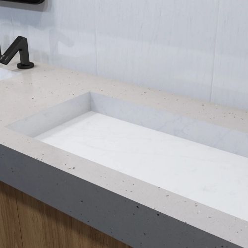Lavabo rectangular de superficie sólida con grifo negro mate, integrado en una encimera gris claro con un mueble de madera.