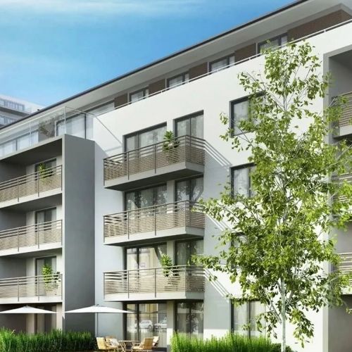 Contemporary residential building with balconies and green landscaping in front.