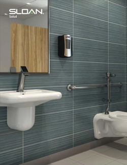 a restroom designed for the healthcare sector, focused on accessibility and sanitation. The wall-mounted sink and toilet feature Sloan automatic faucets and flushometers, providing touch-free hygiene and a functional environment ideal for hospitals and clinics.