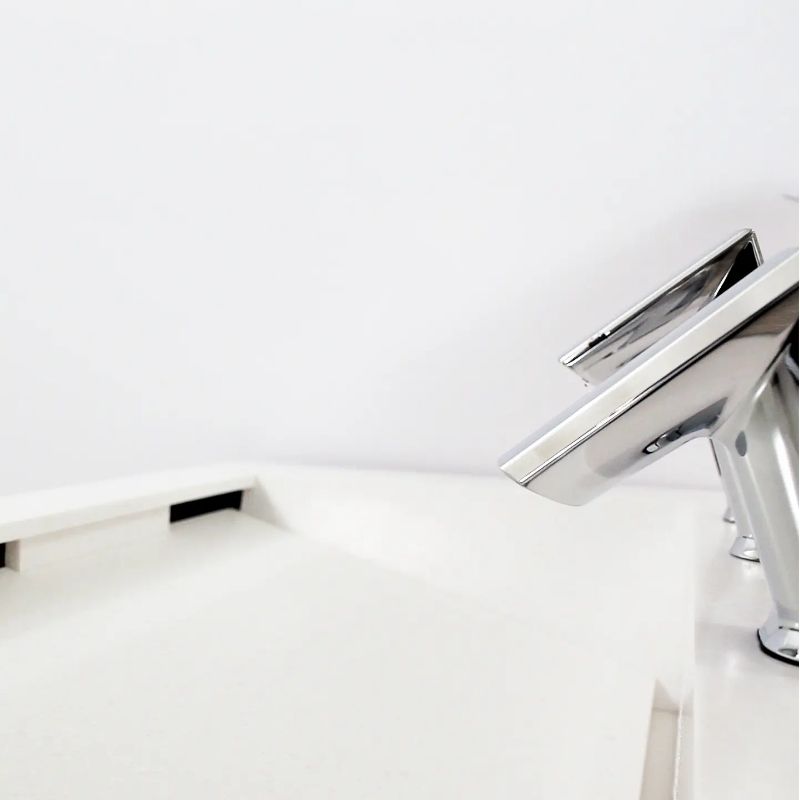 Primer plano de un lavabo blanco con grifos automáticos Sloan cromados y diseño inclinado para un drenaje eficiente.