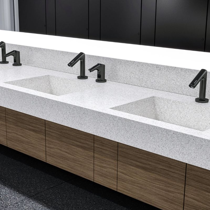 Solid-surface sinks with Sloan sensor-activated faucets in matte black finish, integrated into a modern countertop with wood cabinetry.